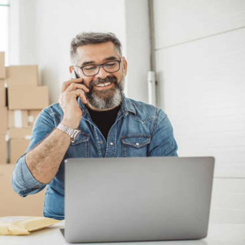 Bearded men working on packaging and online delivery in home office business. He talking on phone with customer